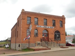 Photo shows the front of the Outlaws and Lawmen Jail Museum, or the Old Teller County Jail. The building is made of bright red bricks, and the windows still have black bars attached to them.